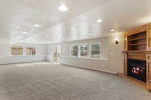 Unfurnished living room featuring carpet and a textured ceiling