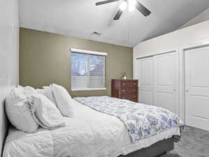 Primary bedroom with lofted ceiling, carpet floors, and ceiling fan