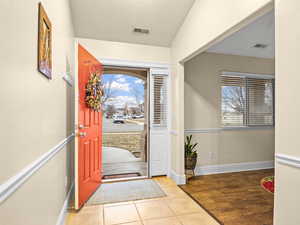 Foyer with light tiles and entry into formal living/Sitting room/Den with laminate wood-look floors