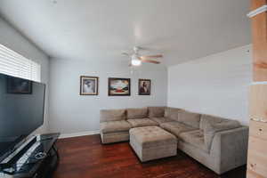 Living room with ceiling fan and dark hardwood / wood-style flooring