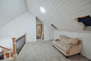 Sitting room with vaulted ceiling, light colored carpet, and wood ceiling