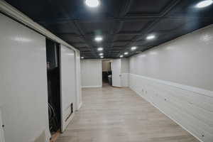 Corridor with coffered ceiling and light wood-type flooring