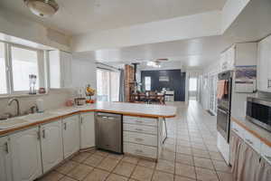 Kitchen featuring stainless steel appliances, white cabinetry, sink, and kitchen peninsula