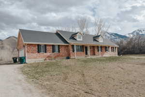 New england style home with a mountain view, a garage, a front lawn, and a porch