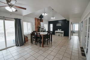 Dining space with ceiling fan with notable chandelier, lofted ceiling, and light tile patterned floors