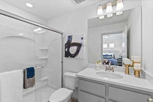 Bathroom with an enclosed shower, vanity, and toilet