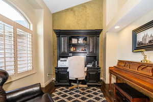 Home office with lofted ceiling and dark hardwood / wood-style floors