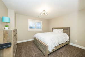 Bedroom with dark colored carpet and a notable chandelier