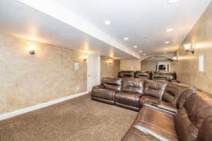 Carpeted cinema room with a textured ceiling