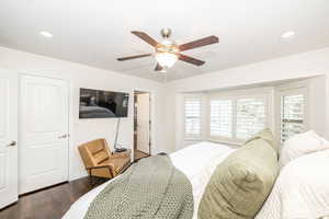 Bedroom featuring multiple windows, dark wood-type flooring, and ceiling fan