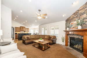 Living room featuring lofted ceiling, a fireplace, plenty of natural light, and ceiling fan