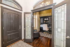 Entryway with dark wood-type flooring and an inviting chandelier