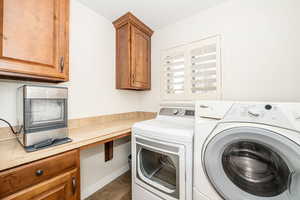 Laundry room featuring tile patterned flooring, cabinets, and washing machine and clothes dryer