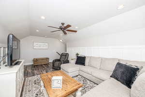 Living room with vaulted ceiling, dark wood-type flooring, and ceiling fan