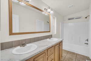 Bathroom featuring tile patterned flooring, vanity, vaulted ceiling, and washtub / shower combination