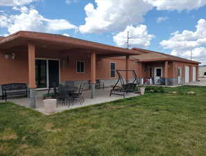 Rear view of house featuring a garage, a patio area, and a lawn