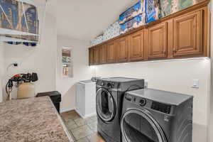 Laundry room featuring cabinets, light tile patterned floors, and independent washer and dryer