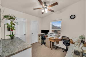 Home office with vaulted ceiling, light colored carpet, and ceiling fan