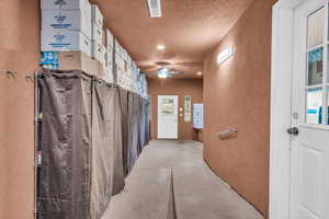 Interior space with ceiling fan, concrete flooring, and a textured ceiling