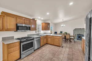 Kitchen with appliances with stainless steel finishes, pendant lighting, sink, a notable chandelier, and kitchen peninsula