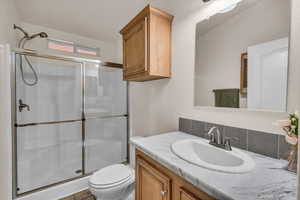 Bathroom featuring vanity, an enclosed shower, and toilet