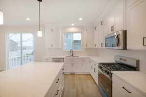 Kitchen featuring a sink, tasteful backsplash, stainless steel appliances, and light wood-type flooring