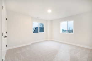 Spare room with baseboards, plenty of natural light, visible vents, and light carpet