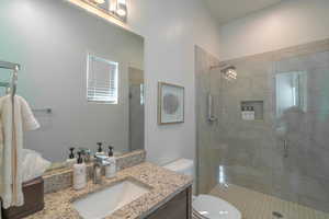 Bathroom with vanity, a shower with door, and toilet