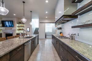 Kitchen with sink, stainless steel appliances, hanging light fixtures, and light stone countertops