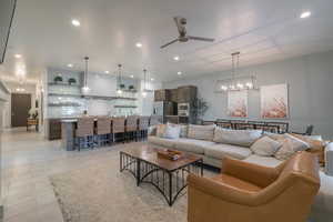 Living room featuring ceiling fan with notable chandelier and light tile patterned floors