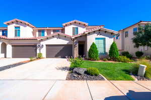 Mediterranean / spanish-style home with a garage and a front lawn