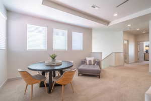 Dining area with light colored carpet and a tray ceiling