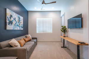 Carpeted living room featuring ceiling fan