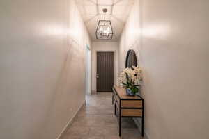 Hall featuring light tile patterned floors and a notable chandelier