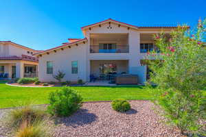 Rear view of house featuring a hot tub, a balcony, a yard, and a patio area