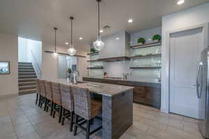 Kitchen with sink, a breakfast bar, light stone counters, a center island with sink, and custom exhaust hood