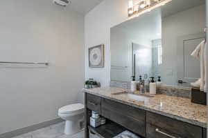 Bathroom featuring tile patterned flooring, vanity, an enclosed shower, and toilet