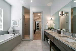 Bathroom featuring vanity, tile patterned floors, and plus walk in shower