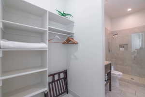 Interior space with tiled shower, vanity, toilet, and tile patterned floors