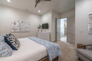 Bedroom featuring ensuite bathroom, light carpet, and ceiling fan