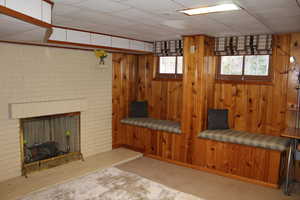 Unfurnished living room with light carpet, a fireplace, and wood walls