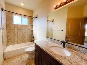 Full bathroom featuring tiled shower / bath, vanity, and toilet