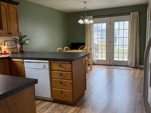 Kitchen featuring hanging light fixtures, hardwood / wood-style floors, white dishwasher, a textured ceiling, and a chandelier