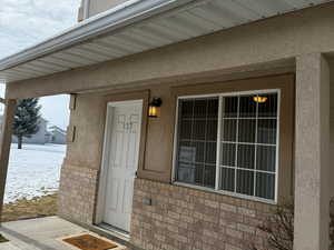 View of exterior entry featuring brick siding and stucco siding