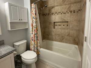 Full bathroom featuring shower / bath combo, tile patterned flooring, vanity, a textured ceiling, and toilet