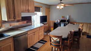 Kitchen featuring dishwashing machine, a kitchen bar, ceiling fan, light hardwood / wood-style floors, and crown molding