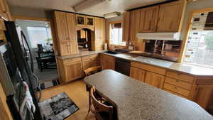 Kitchen with sink, backsplash, black appliances, and light wood-type flooring