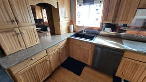 Kitchen with sink, light hardwood / wood-style flooring, stovetop, dishwasher, and stone counters