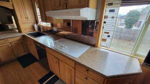 Kitchen with white stovetop, sink, and a wealth of natural light