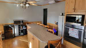 Kitchen featuring appliances with stainless steel finishes, a breakfast bar area, light stone counters, and light brown cabinetry